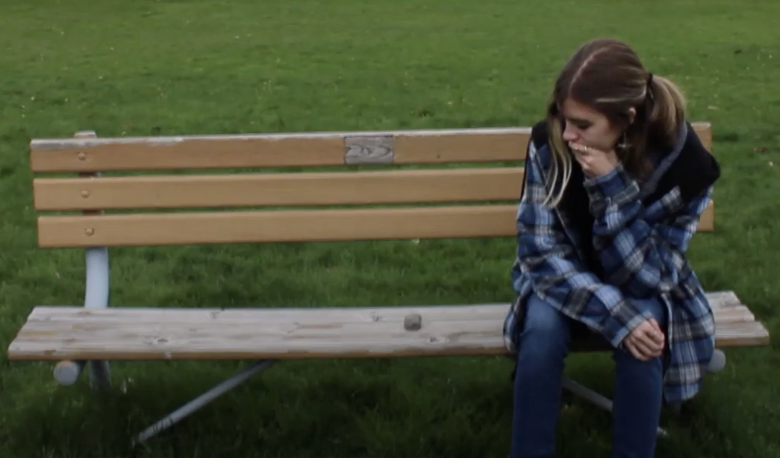 woman contemplating a rock that is "sitting" on a park bench beside her