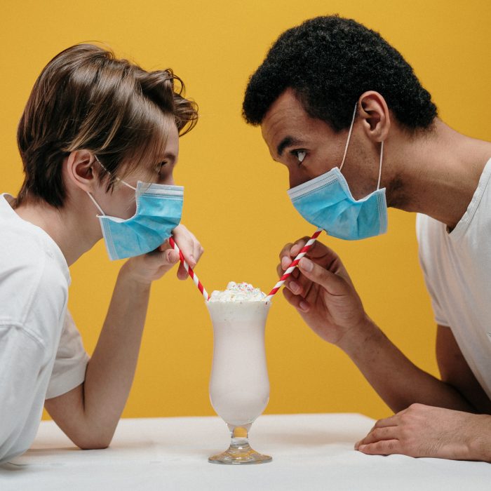 two masked people drinking from the same milkshake