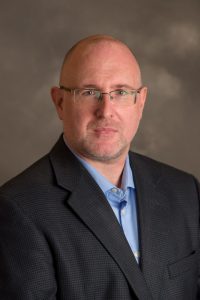 portrait: bald white man with light beard, mustache, and glasses