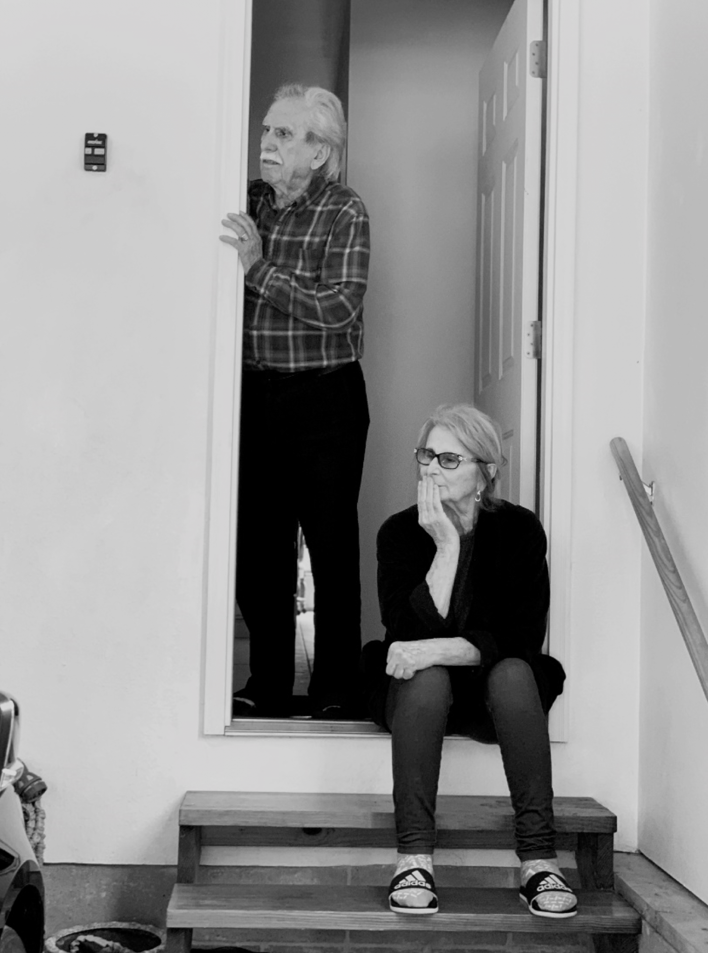 elderly couple sitting/standing just outside their front door